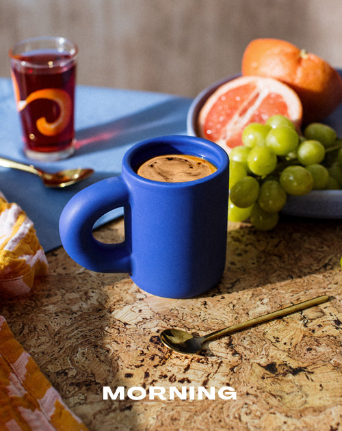 coffee in blue mug surrounded by breakfast fruit with text 